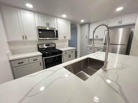 A kitchen with white cabinets and a stainless steel refrigerator.