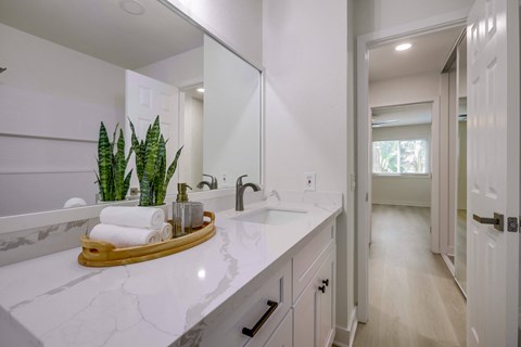 A bathroom with a white counter top and a wooden tray holding toiletries.