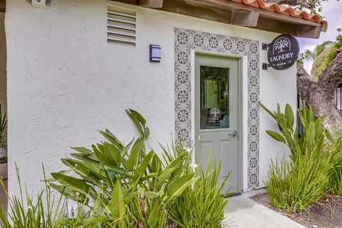 A white building with a green door and a sign that says "Laundry".
