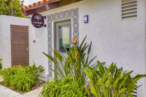 A white building with a brown door and a window with a decorative frame.