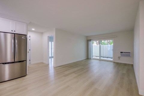 A kitchen with a refrigerator and a wooden floor.