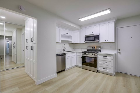 A kitchen with white cabinets and a wooden floor.