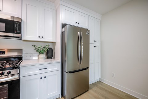 A kitchen with a stainless steel refrigerator and white cabinets.