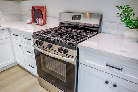A modern kitchen with a stainless steel stove and white cabinets.