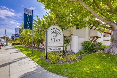 A sign for VIVA Apartment Homes is in front of a building.