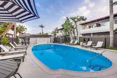 A swimming pool surrounded by lounge chairs and umbrellas.
