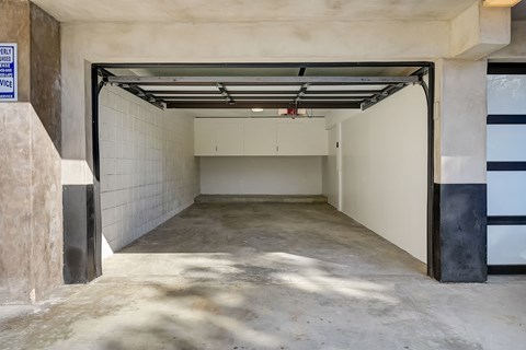 A spacious garage with a white wall and a black door.