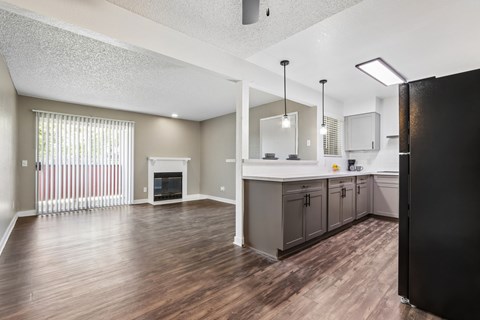 A kitchen with a black refrigerator and wooden floors.