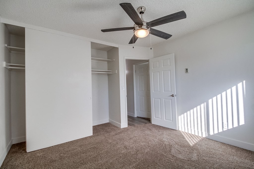 a bedroom with a ceiling fan and walk in closet