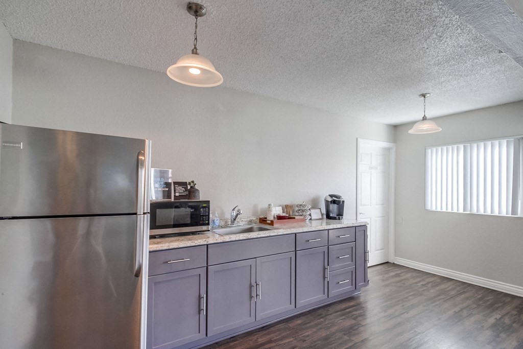a kitchen with gray cabinets and a stainless steel refrigerator