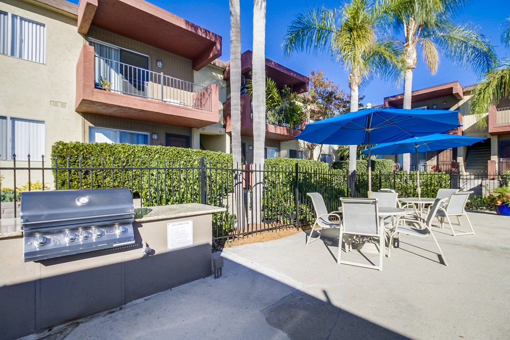a patio with a grill and tables and umbrellas