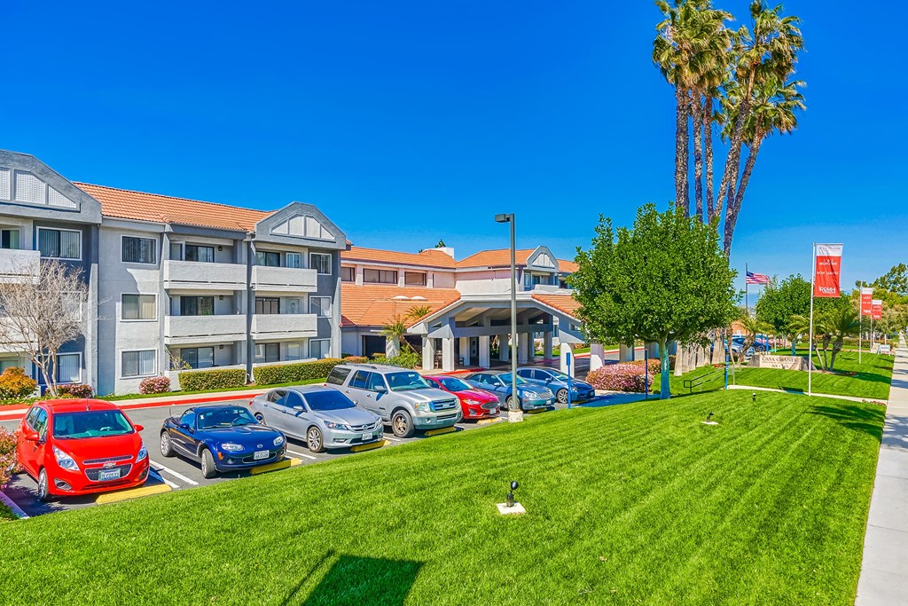 a grassy area with cars parked in front of a building