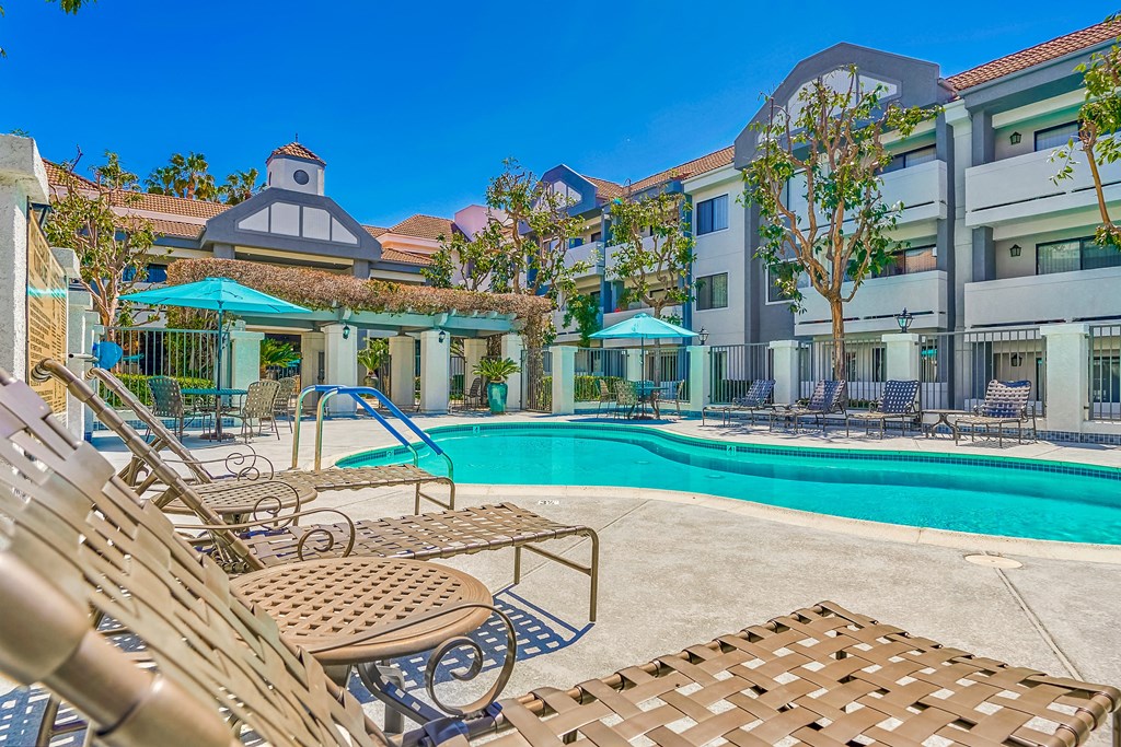 a swimming pool with lounge chairs and umbrellas in front of a building