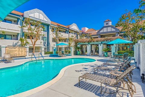 a swimming pool with lounge chairs and umbrellas