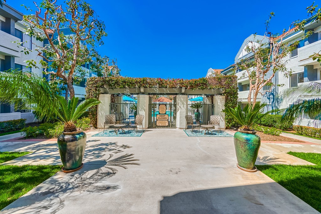 a courtyard with a building in the background and two large vases on the side of the