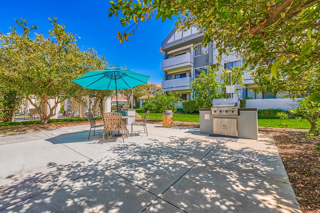 a patio with a grill and umbrella