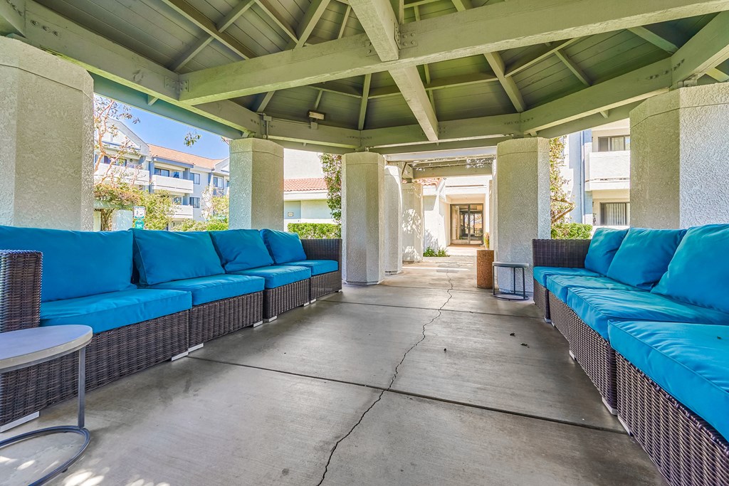 a covered patio with blue couches and tables