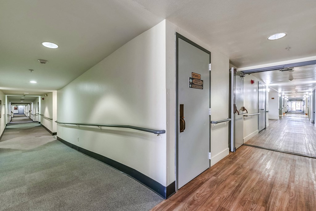 a hallway with white walls and wood flooring