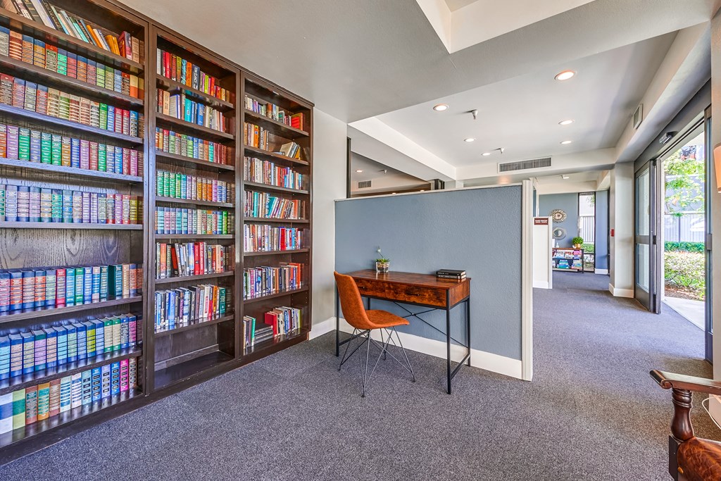 a home library with a desk and chair in front of a large bookshelf