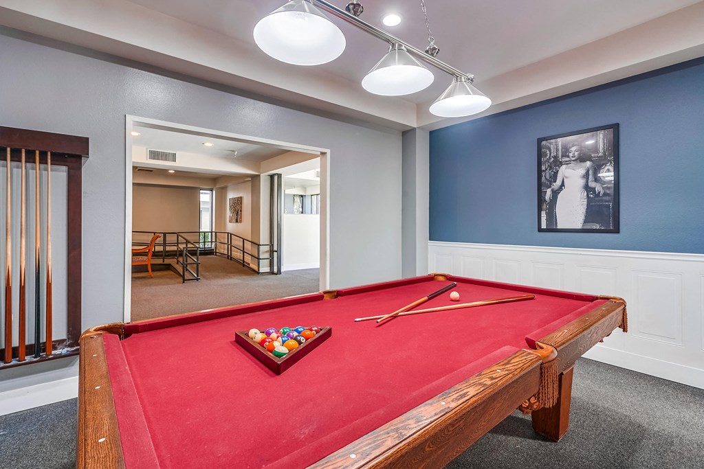 a red pool table in a blue room with a black and white picture on the wall