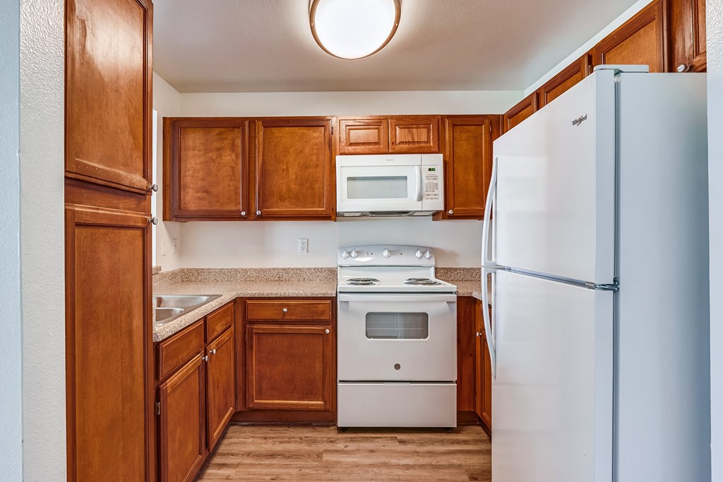 a kitchen with brown cabinets and white appliances