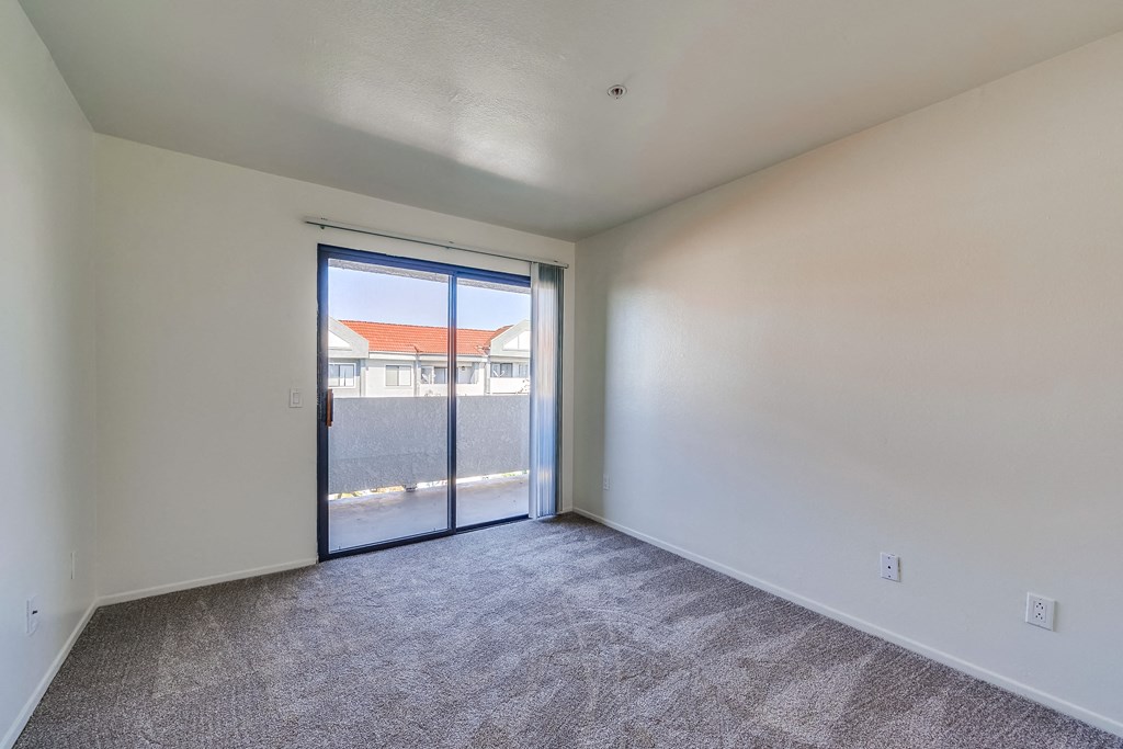a bedroom with a sliding glass door and carpeted floor