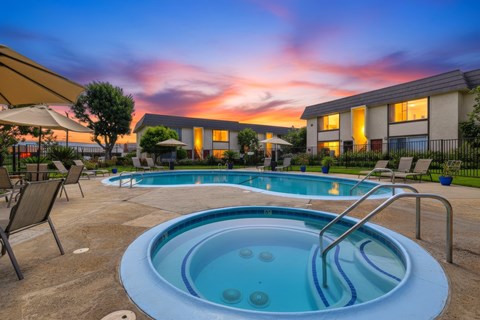 A hot tub sits in the middle of a patio with chairs around it.