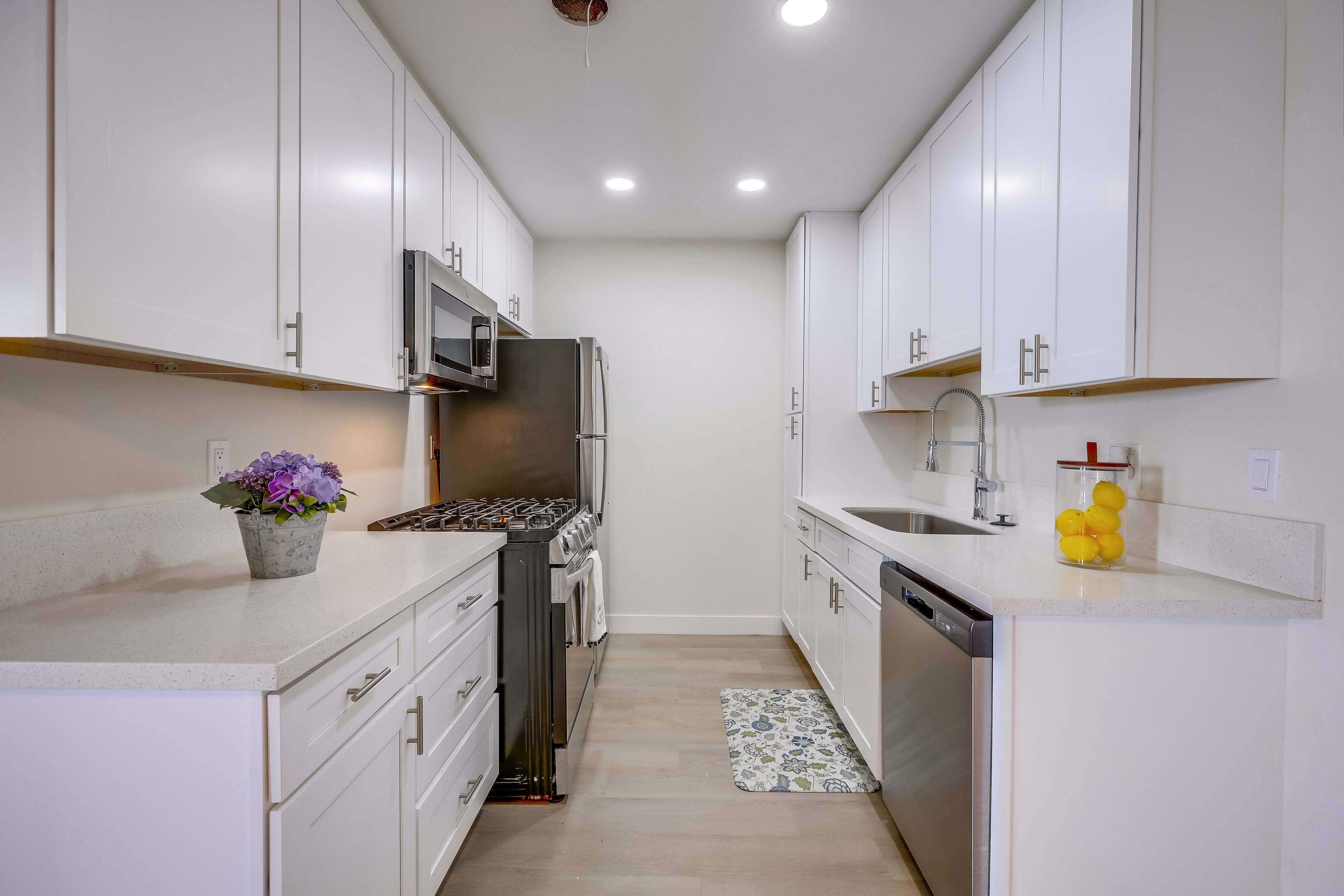 A kitchen with white cabinets and a black refrigerator.