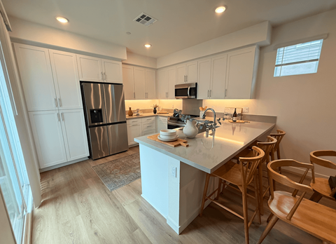 A kitchen with a white counter and wooden chairs.