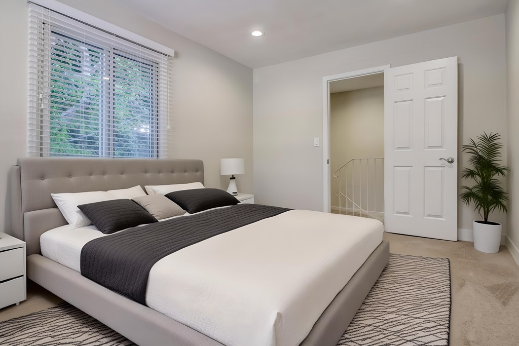 A bedroom with a large bed and a window with blinds.