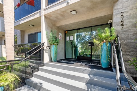 A modern building entrance with a glass door and steps leading up to it.