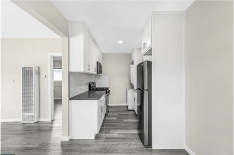 A kitchen with white cabinets and a black countertop.