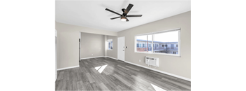 A spacious room with a ceiling fan and a large window.