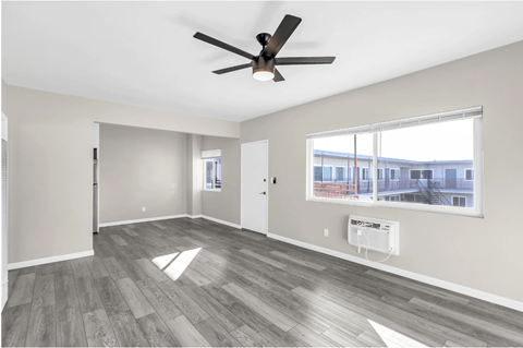 A spacious room with a ceiling fan and a large window.