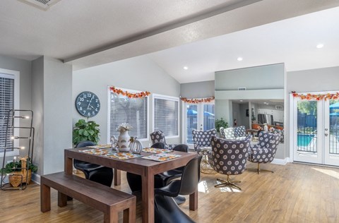 A dining room with a table set for four and a clock on the wall.