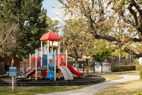 A playground with a red and blue slide and a red and yellow tower.