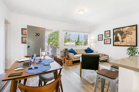 A dining room with a table set for four and a couch with a pillow.