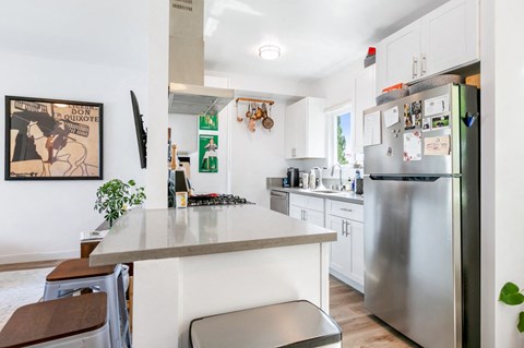 A kitchen with a stainless steel refrigerator and a person cooking.
