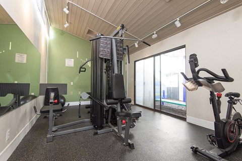 A gym with a treadmill, elliptical trainer and a stationary bike.