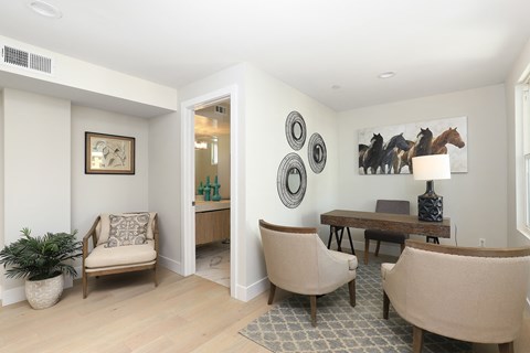 A living room with a chair, a table, and a painting on the wall.