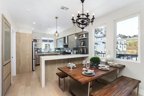 A modern kitchen with a dining table set for two.