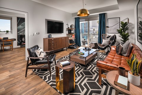 A living room with a black and white rug and a brown leather couch.
