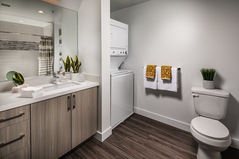 A bathroom with a toilet, sink, and mirror.