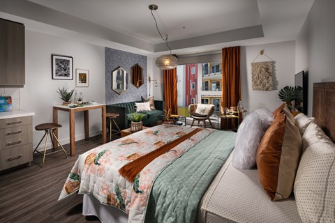 A bedroom with a bed, a desk, and a chair.