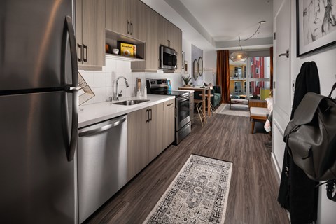 A modern kitchen with a refrigerator on the left and a dining area in the background.