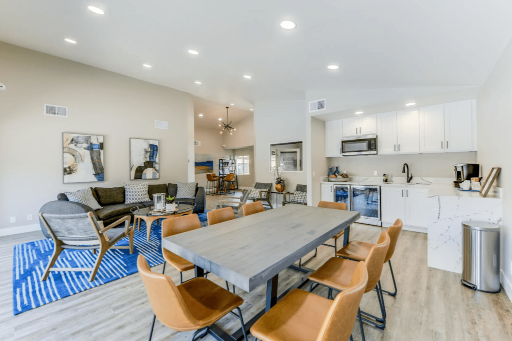 a dining room table with chairs and a kitchen in the background