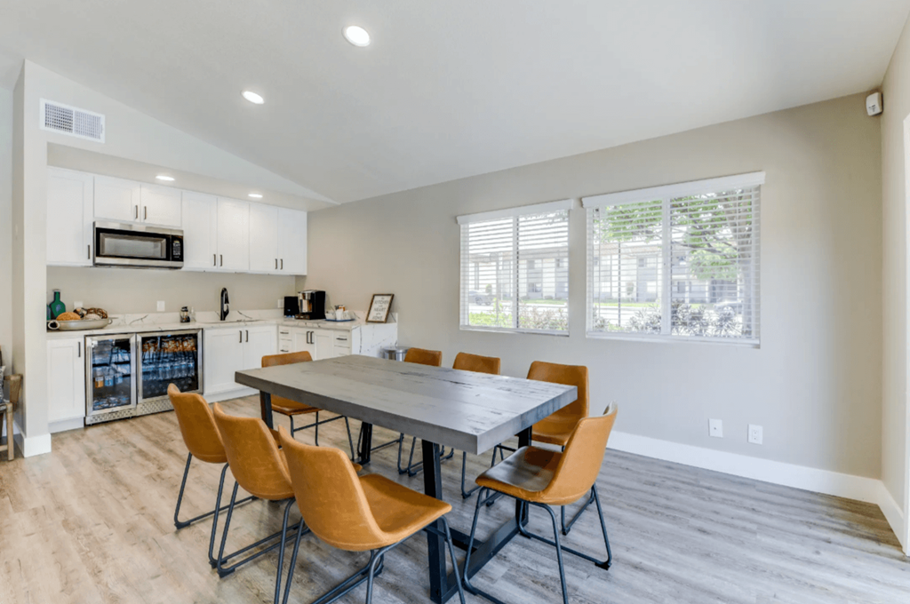 a dining area with a table and chairs and a kitchen in the background