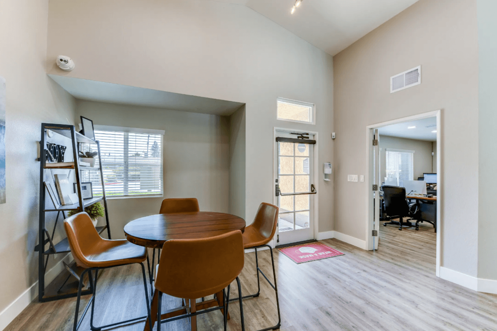 a dining area with a round table and four orange chairs