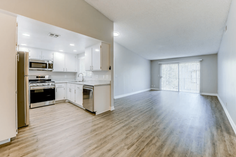 A kitchen with white cabinets and a wooden floor.