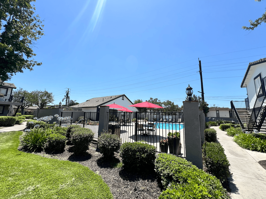 a yard with a pool and a fence and some umbrellas